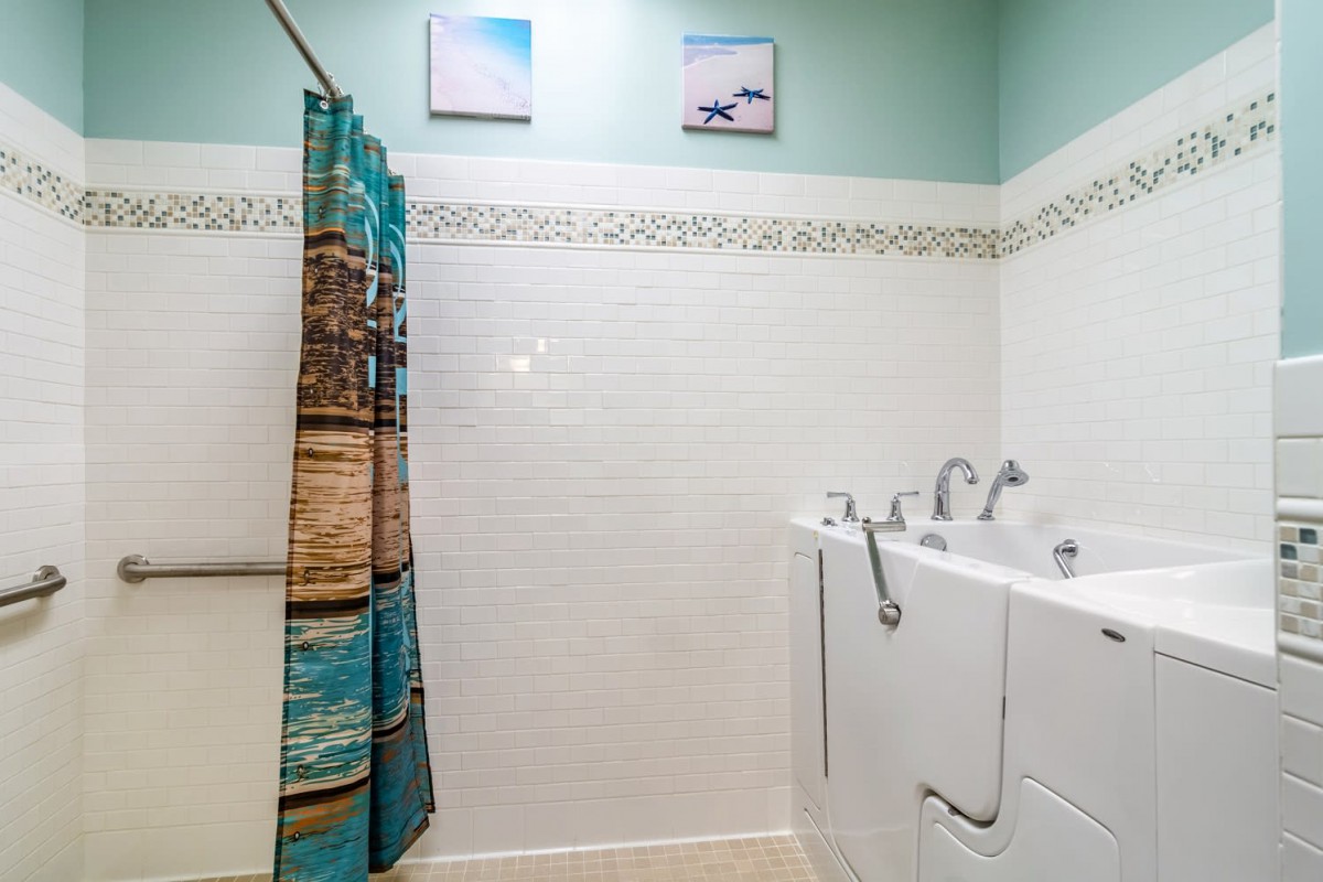 A well-designed bathroom featuring a walk-in tub with a colorful shower curtain and decorative tiles.