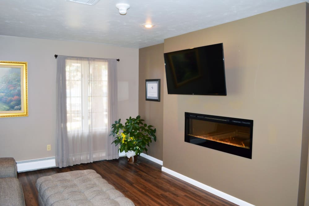 A cozy living room with a mounted television and modern fireplace.