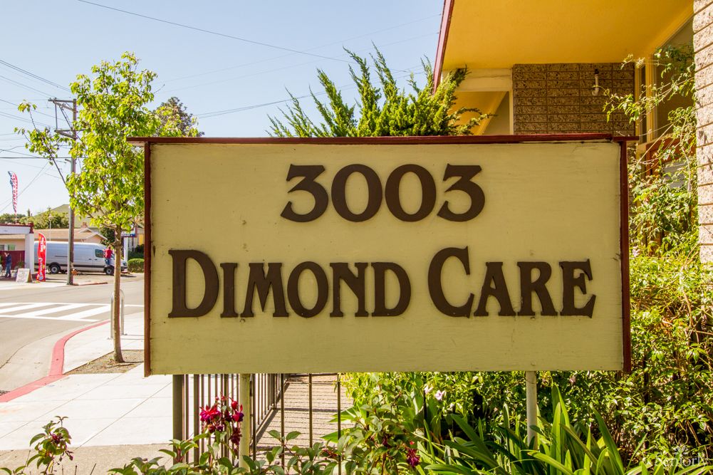 A sign displaying the address '3003 Dimond Care' in front of a building with surrounding greenery.
