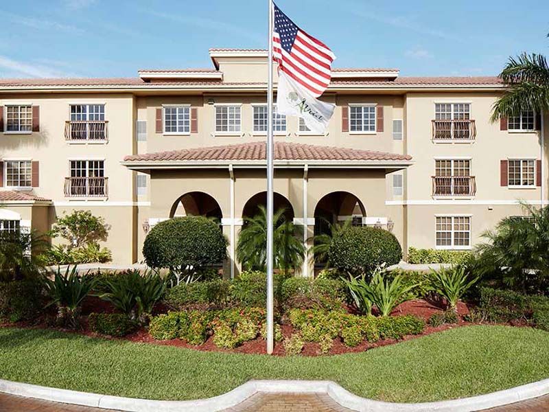 A building with an American flag in front, surrounded by well-maintained greenery.