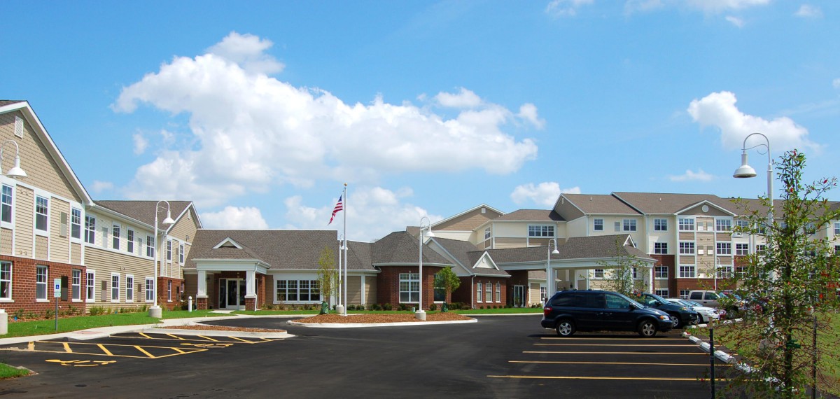 A residential building with a parking lot under a partly cloudy sky.