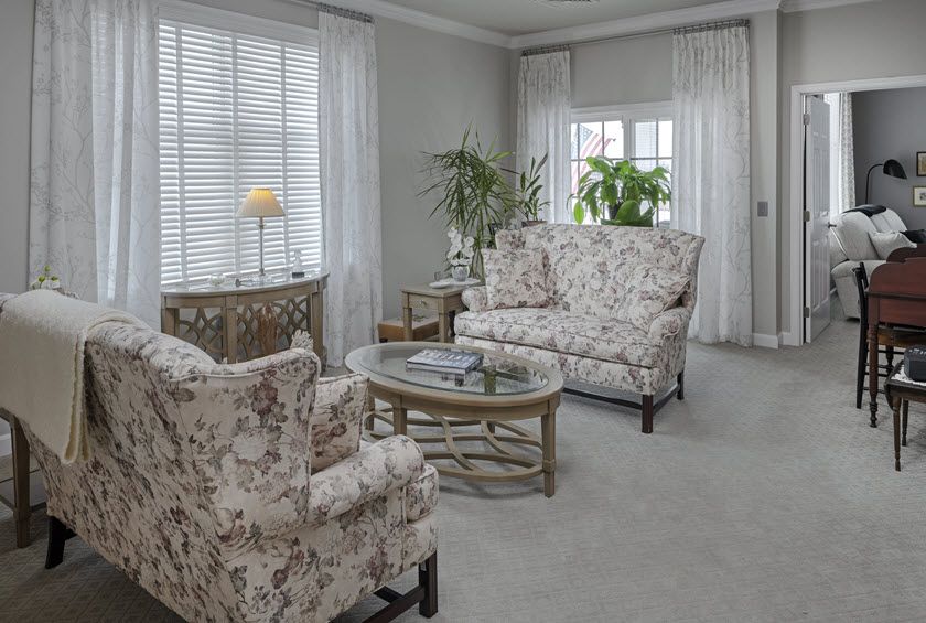 A cozy living room with floral-patterned furniture and natural light.
