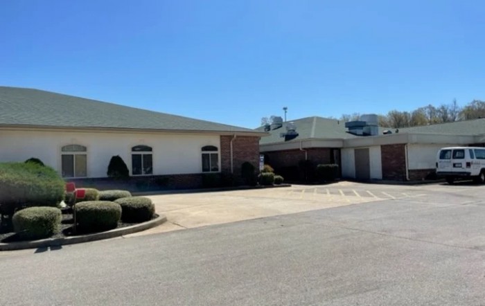 A view of a building with a parking lot under a clear blue sky.