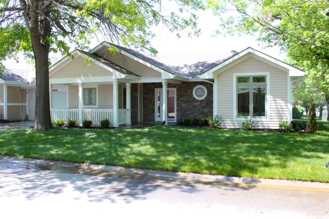 A charming suburban house with a well-maintained lawn and surrounding trees.