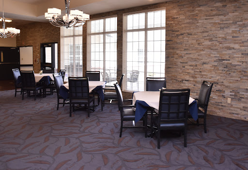 A spacious dining area featuring modern tables and chairs, illuminated by natural light from large windows.
