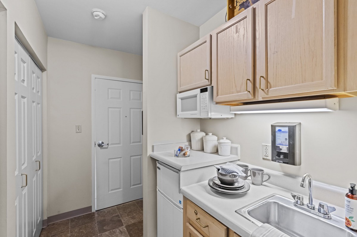 A small apartment kitchen with light-colored cabinets and essential appliances.