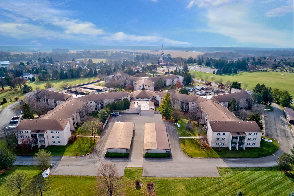 Aerial view of a residential apartment complex with surrounding greenery and parking areas.