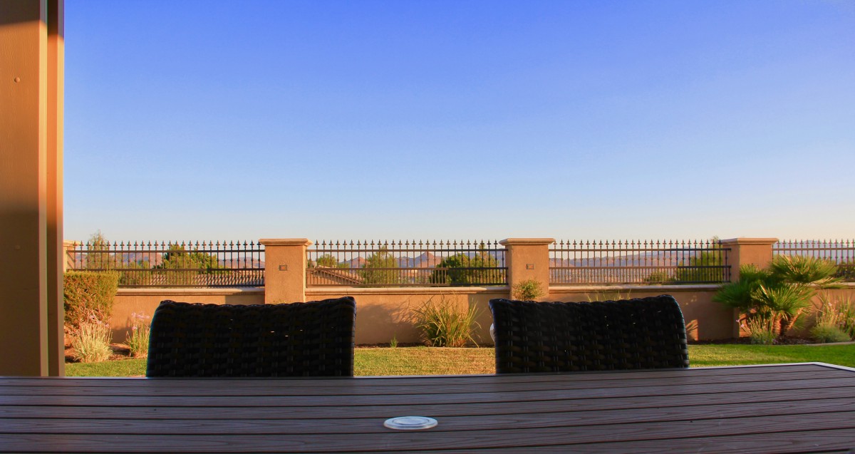 A serene view from a patio overlooking a fence under a clear blue sky.