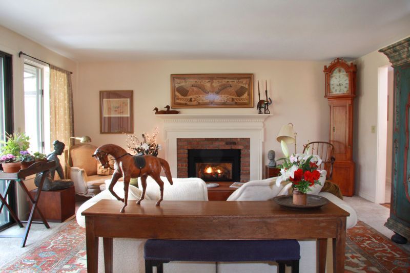 A cozy living room with a fireplace, elegant decor, and a wooden horse sculpture on the table.