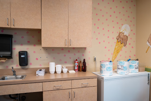 A cozy kitchen corner featuring light wood cabinets, various utensils, and playful wallpaper.