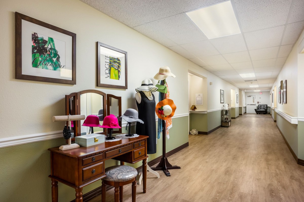 A hallway with decorative hats and furniture, featuring framed artwork on the walls.