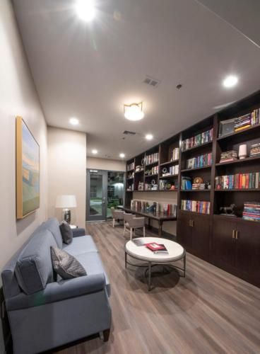 A modern library with built-in bookshelves, a comfortable sofa, and a round table.