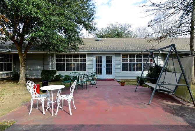 A cozy backyard patio with outdoor furniture and a swing.