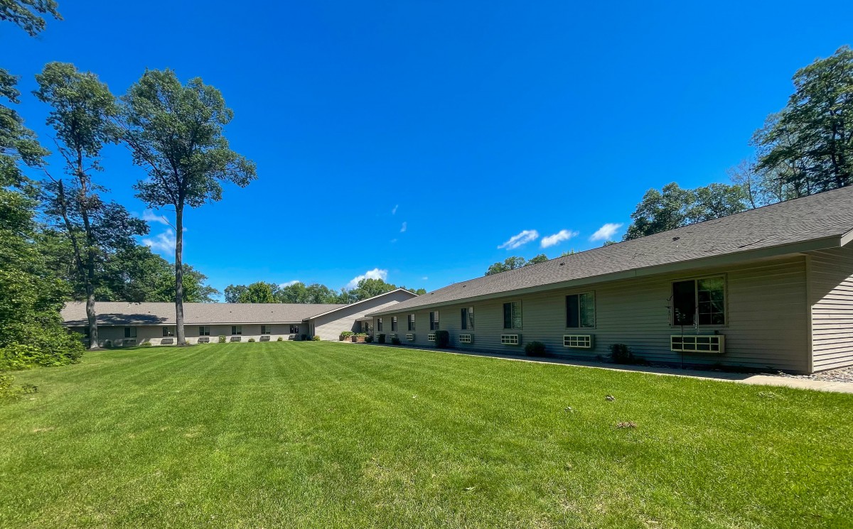 A long building with a well-maintained lawn under a clear blue sky.
