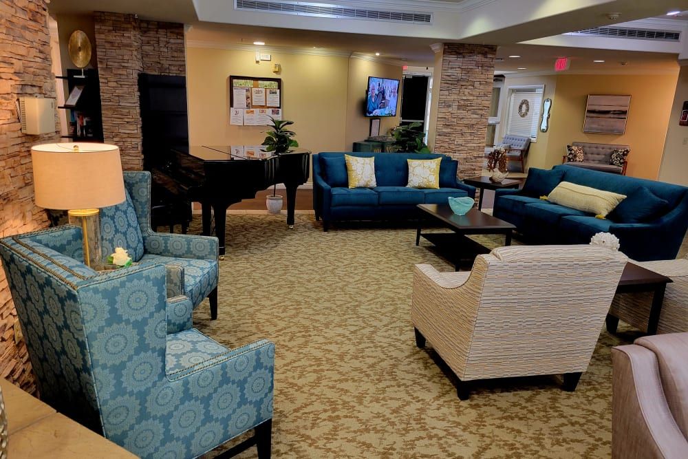 A comfortable lounge area with sofas, armchairs, a piano, and a television.