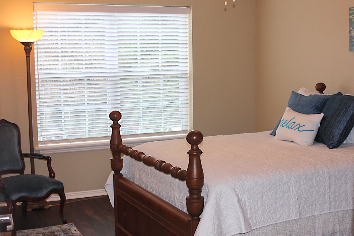 A cozy bedroom with a wooden bed frame and a window with blinds.