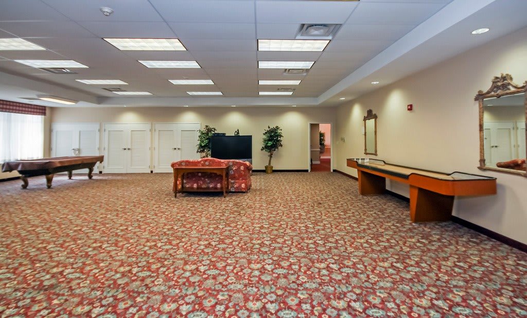 A spacious lounge area with comfortable seating, a television, and decorative plants.