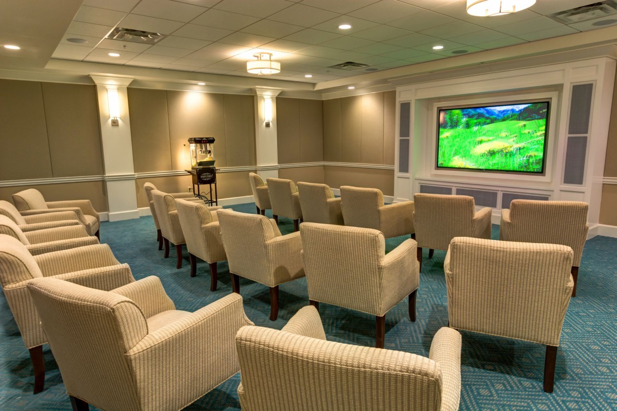 A cozy home theater room with rows of comfortable chairs facing a large screen.