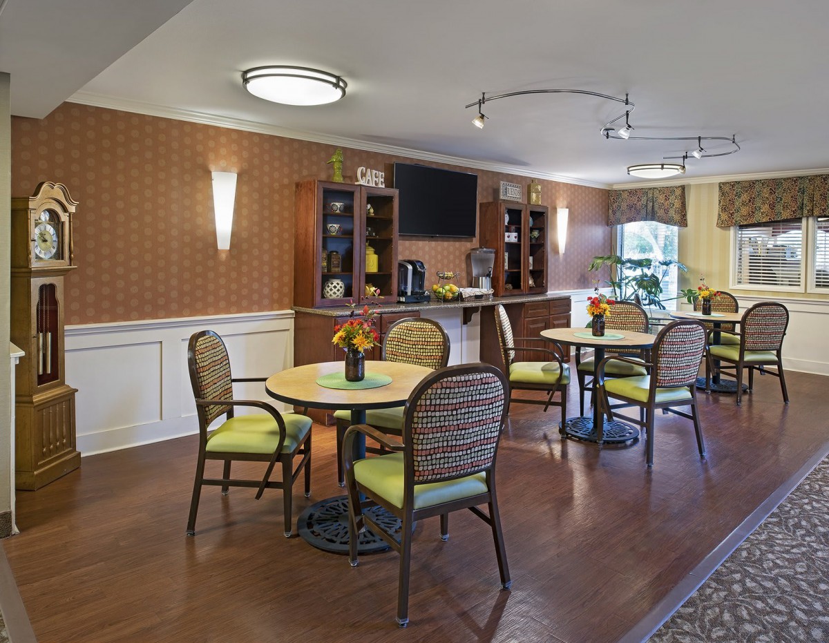 A cozy dining area with neatly arranged tables and chairs, featuring warm lighting and elegant wall decor.