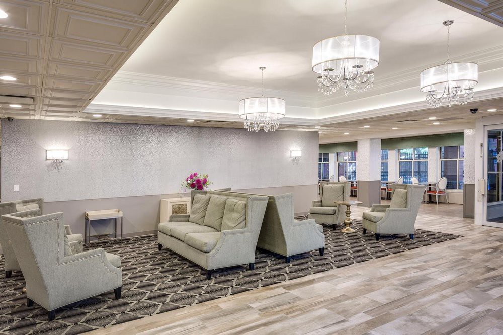 A modern lobby area featuring elegant sofas, chandeliers, and a patterned carpet.