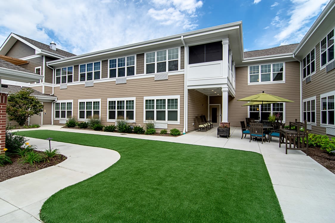 A modern residential building with a well-maintained lawn and outdoor seating area.
