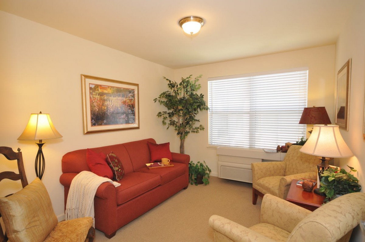 Cozy living room with a red sofa and beige armchairs.