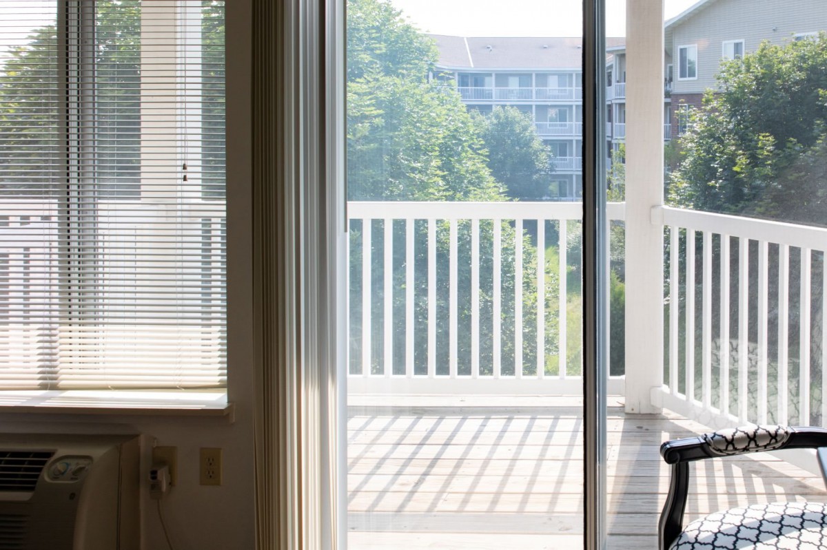 A sunny view of a balcony through a sliding glass door.