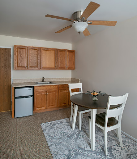 A cozy kitchen and dining area featuring wooden cabinets, a small table with chairs, and a ceiling fan.