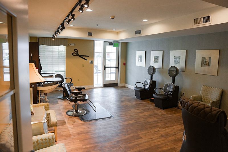 A modern hair salon interior featuring barber chairs and hair dryers on a wooden floor.