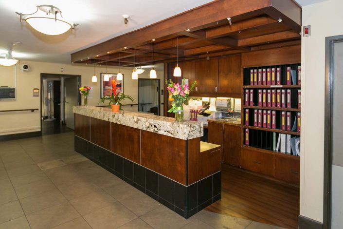 A well-organized reception desk in an office setting, featuring wood paneling and decorative flowers.