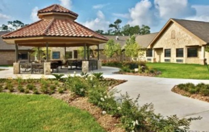 A beautiful garden with a gazebo and paved pathway leading to adjacent buildings.