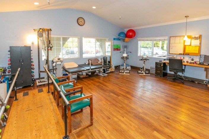 A well-equipped physical therapy room with exercise equipment and seating area.