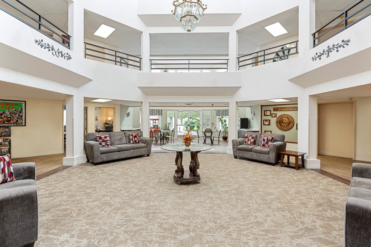 A spacious and luxurious living room with elegant furniture and a central chandelier.
