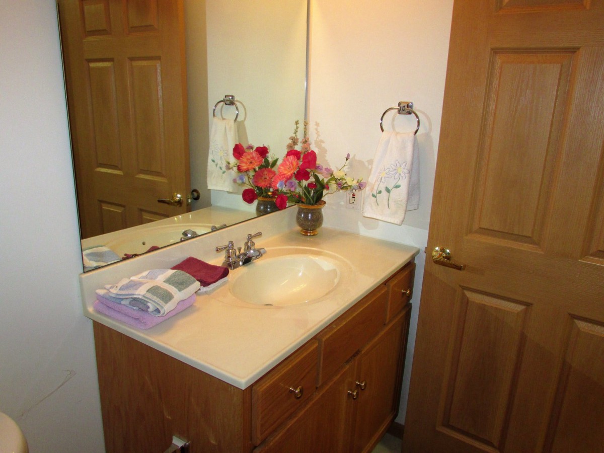 A neatly arranged bathroom vanity with a mirror, decorated with flowers and towels.