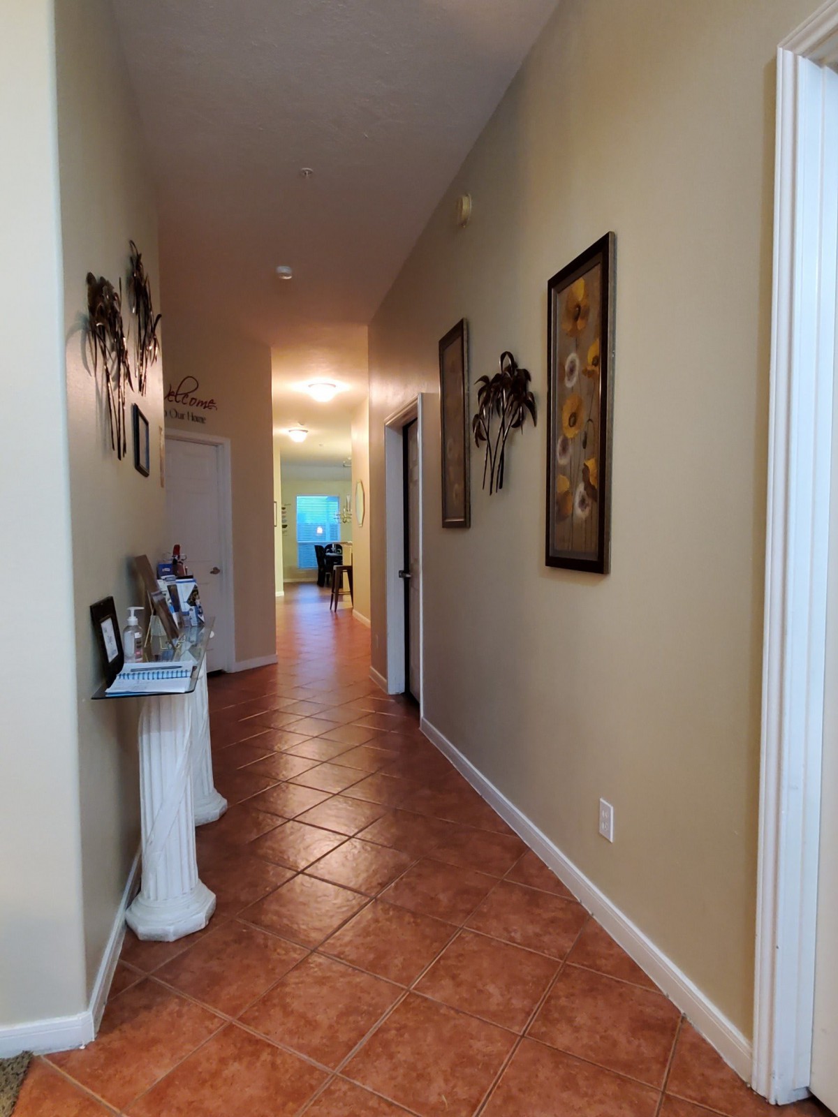 A well-lit hallway with decorative artwork and tiled flooring.