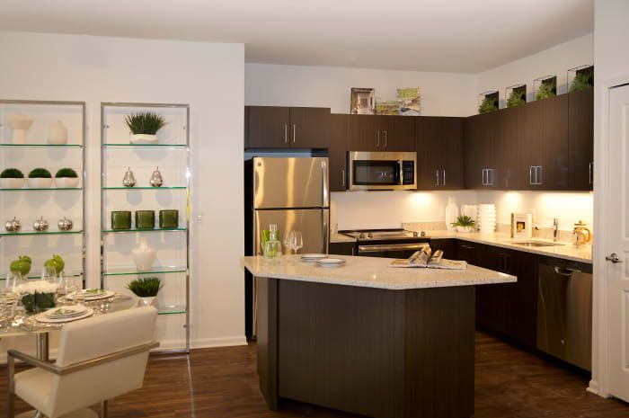 A modern kitchen with dark cabinets and a central island, featuring stainless steel appliances.