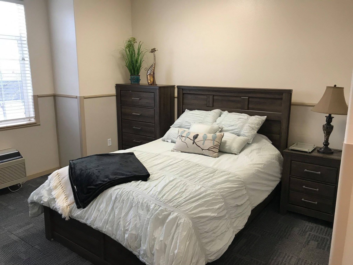A cozy bedroom with a neatly made bed and wooden furniture.