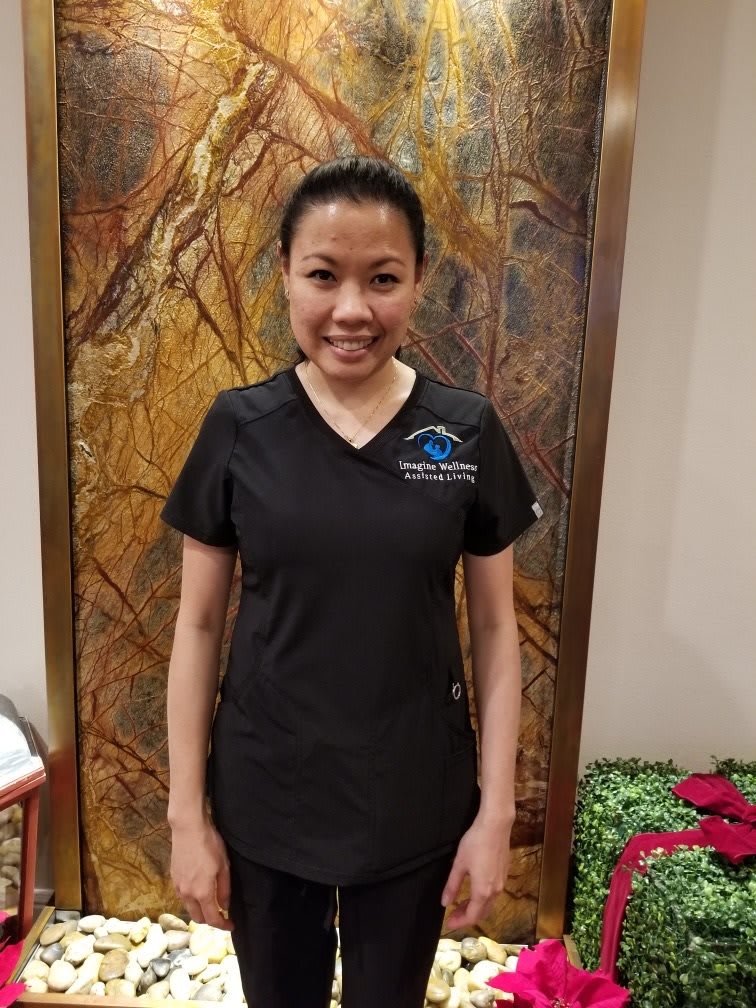 A person standing indoors wearing a uniform and smiling.