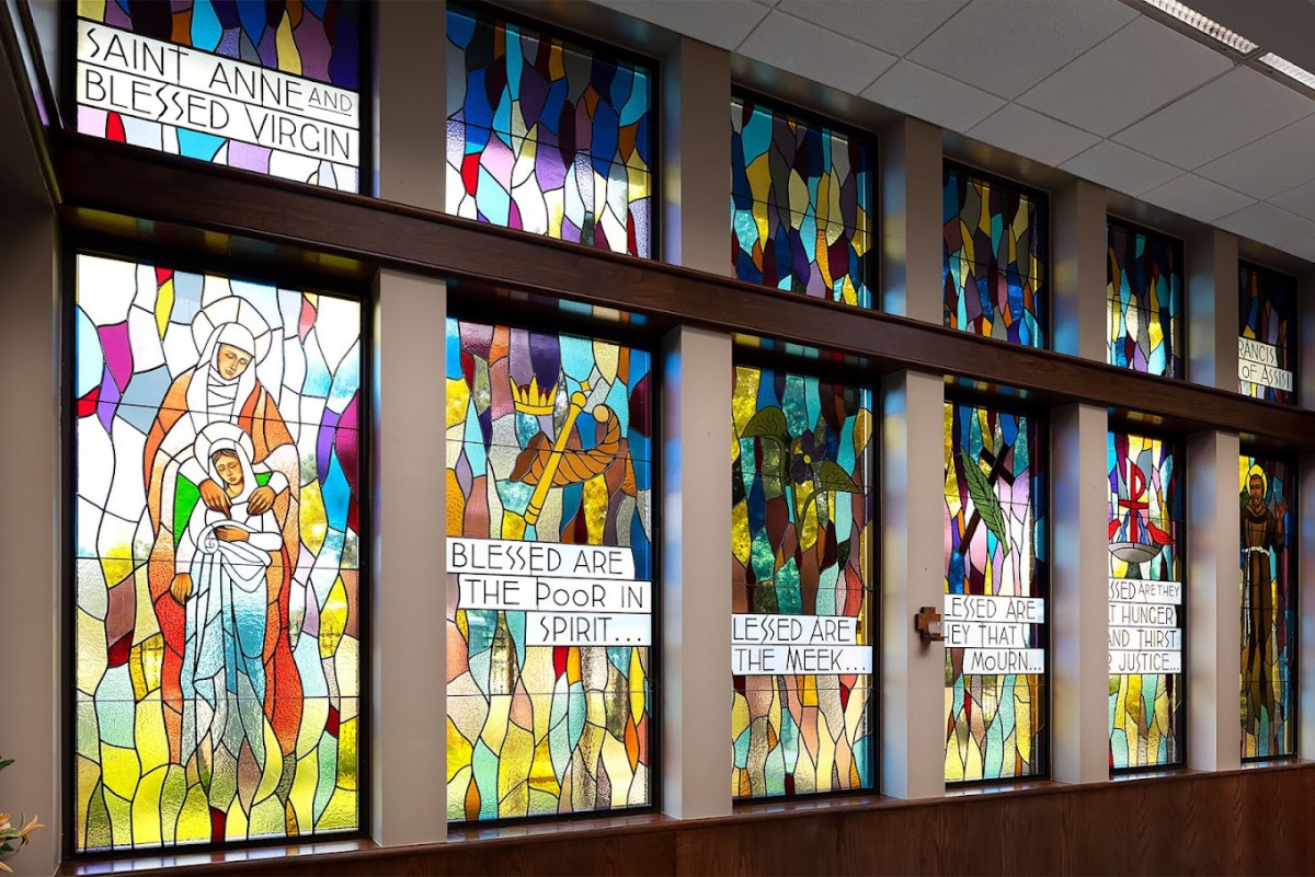 A series of colorful stained glass windows with abstract designs in a church setting.