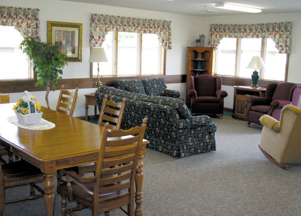 A cozy living room with a sofa, armchairs, and a dining table near large windows.