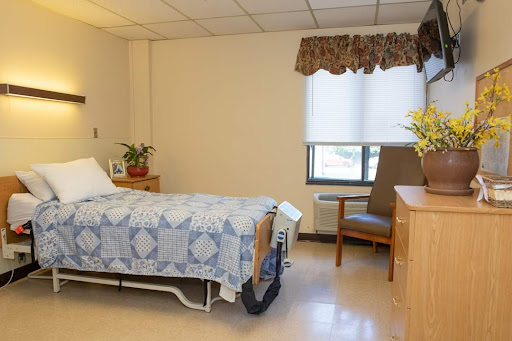 A well-lit hospital room featuring a patient bed, chair, and decorative elements.