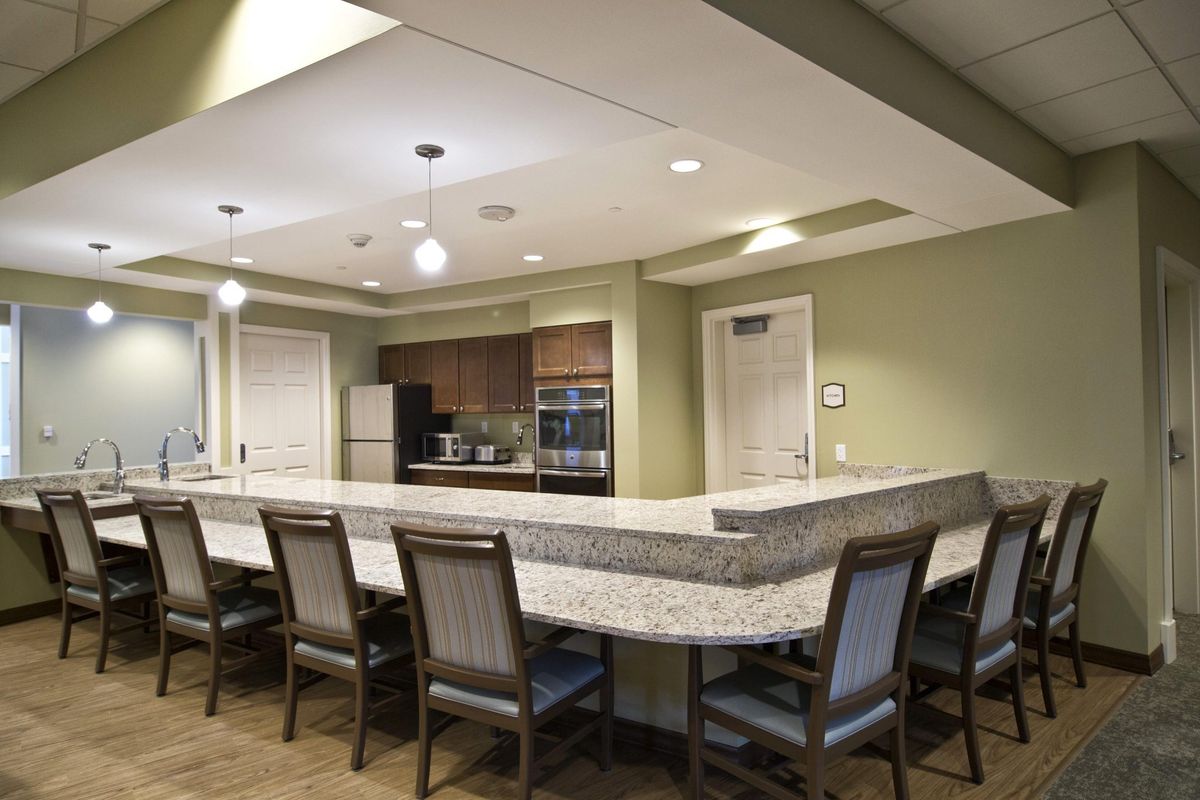 Modern kitchen interior with a large counter and several chairs.