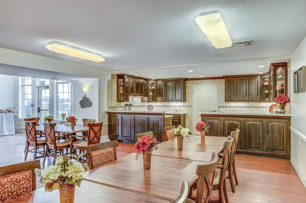 A cozy kitchen and dining area with wooden tables and chairs, decorated with floral centerpieces.