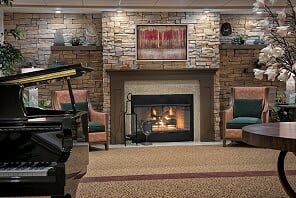 A cozy living room with a stone fireplace, comfortable armchairs, and warm decor.