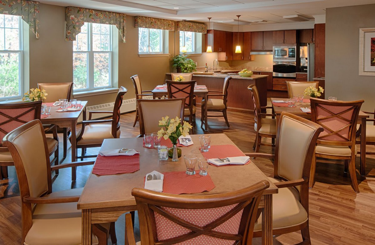 Elegant dining area with neatly arranged tables and chairs adjacent to a modern kitchen.