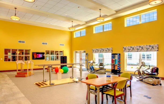 A brightly lit rehabilitation center featuring various therapy equipment and seating areas.