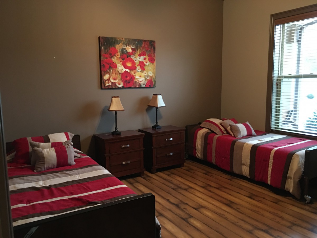 A cozy bedroom with twin beds, nightstands, and a decorative painting.