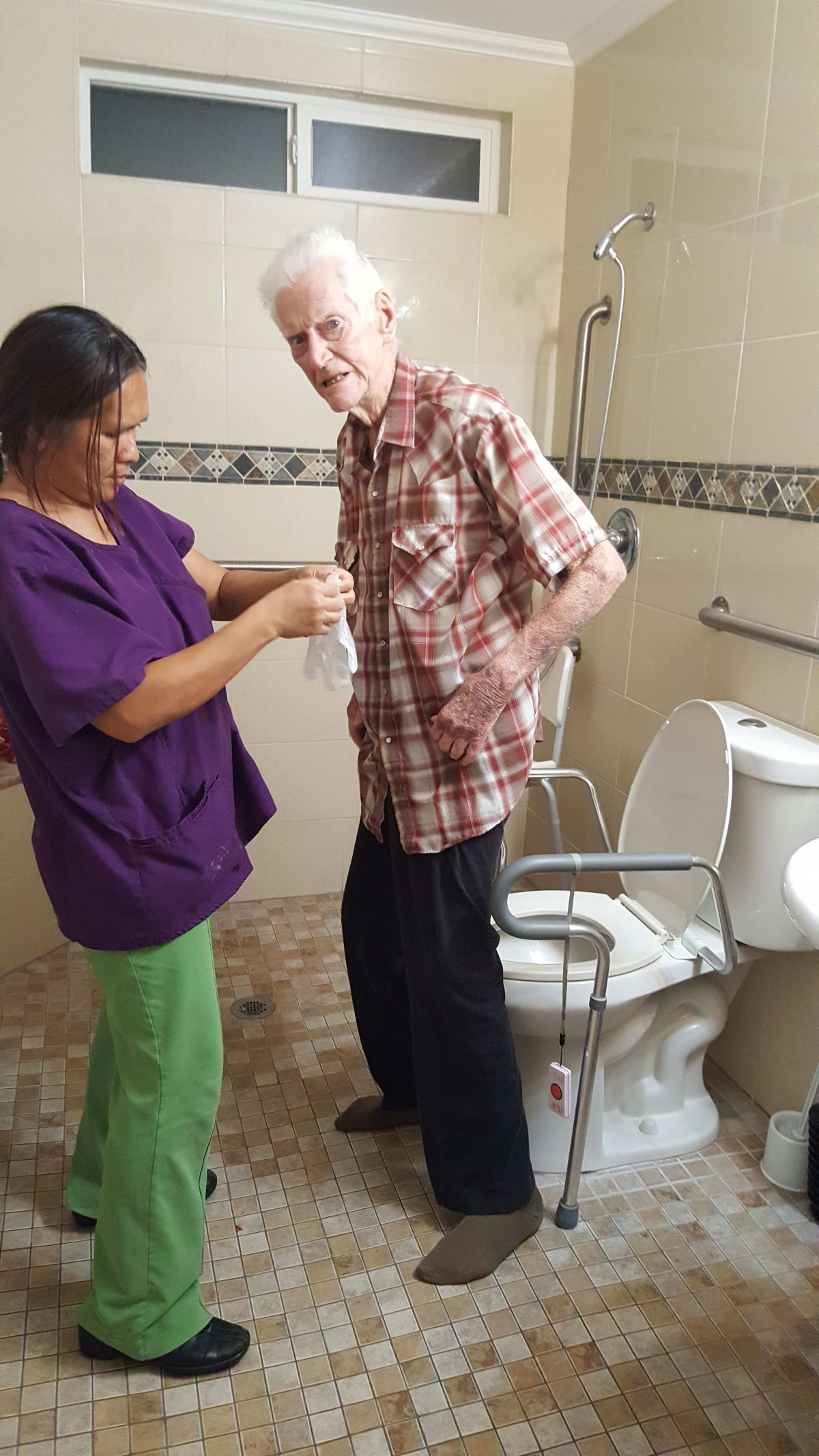 A caregiver assists an elderly person in the bathroom.