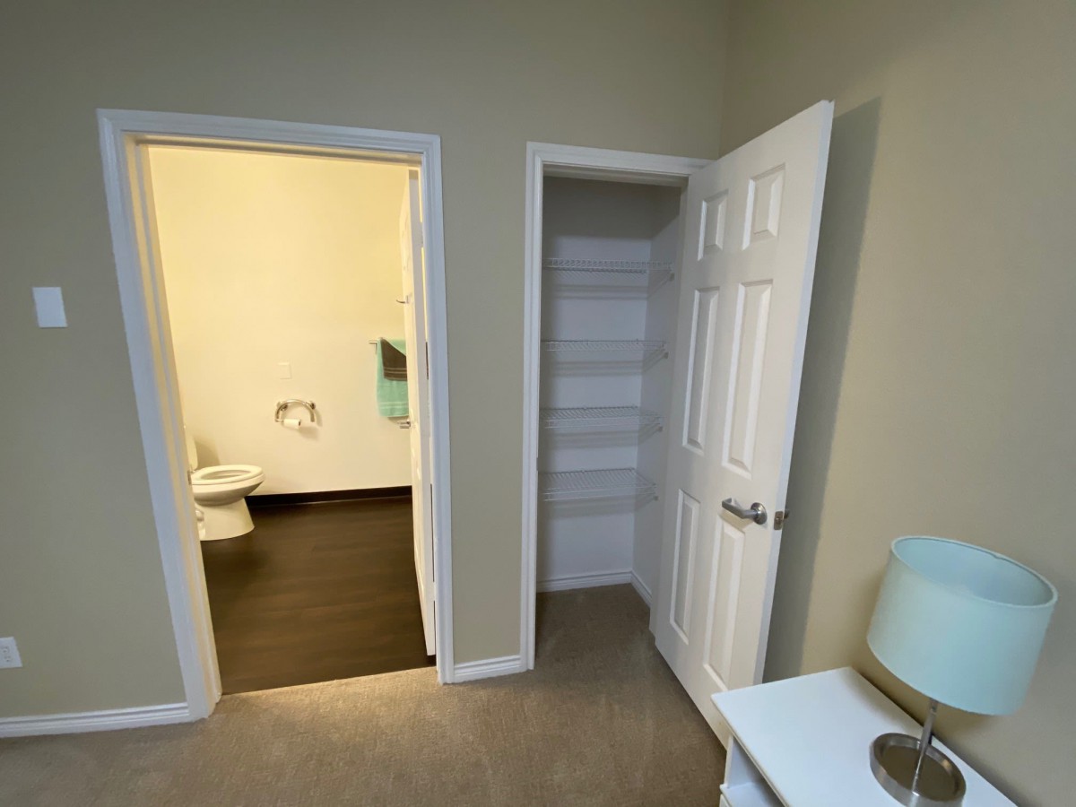 A view of an interior room with an open closet door and a bathroom entrance.