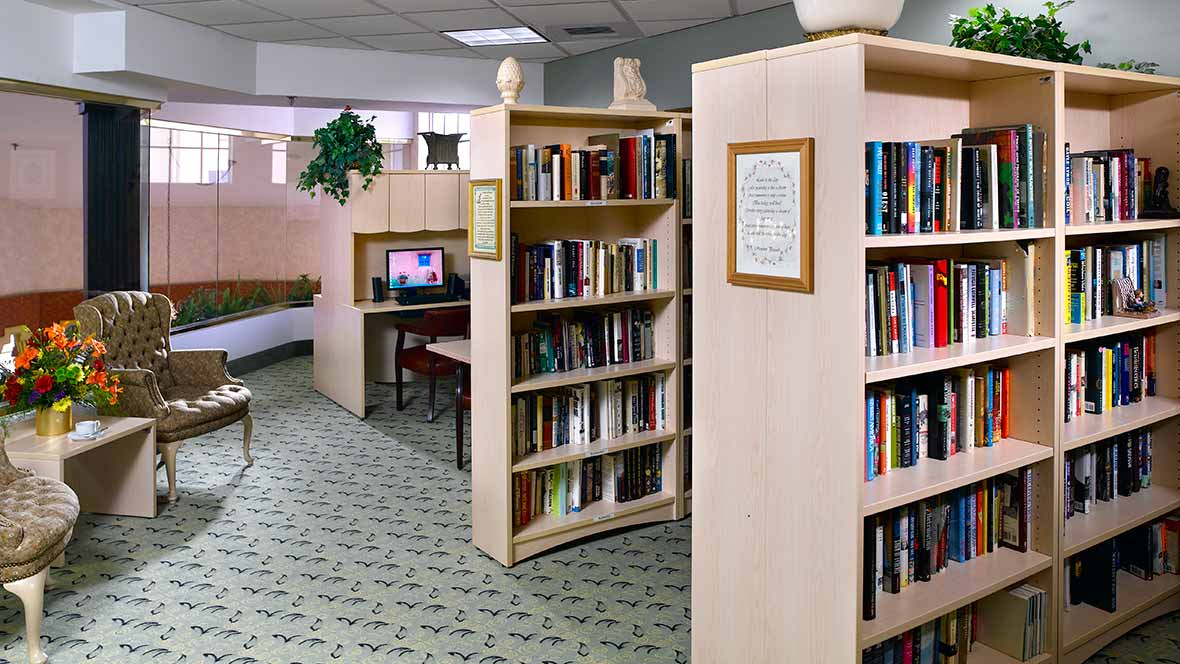 A cozy library corner featuring shelves filled with books and a computer station.
